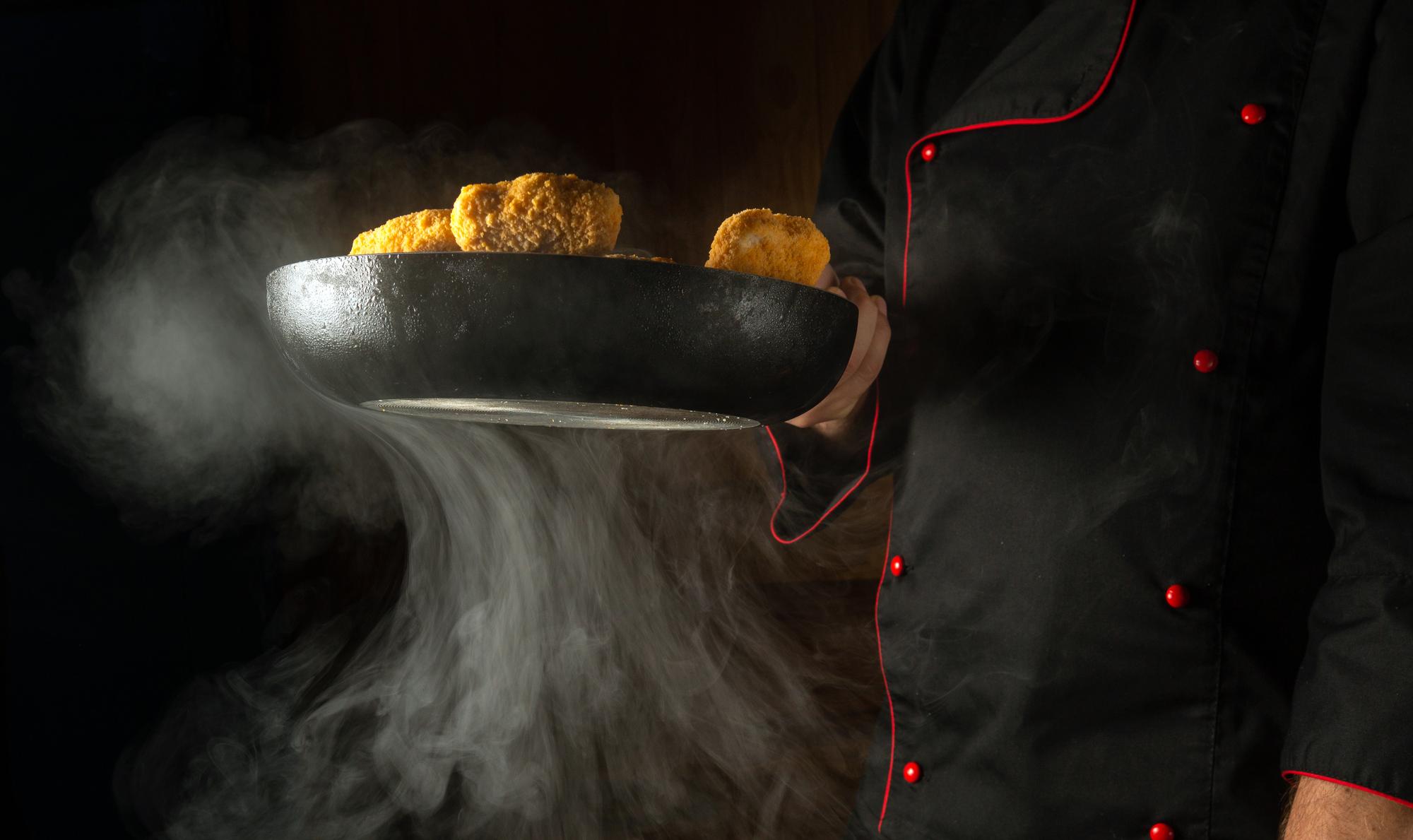 Chef at work with open flame and stainless pans